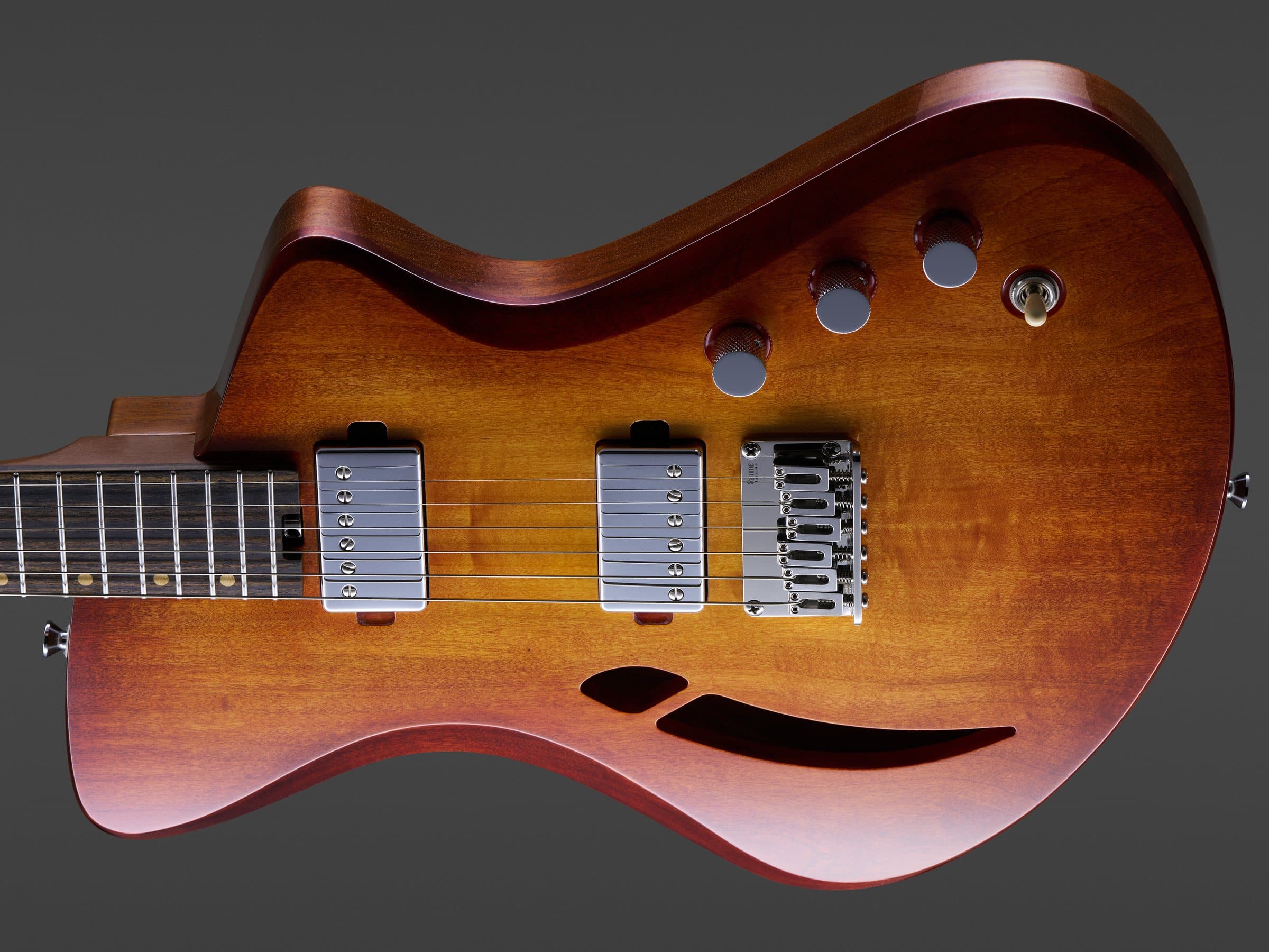 Corpo de uma guitarra Sallowicz Fluid deitada, com o F-hole e a ponte em destaque